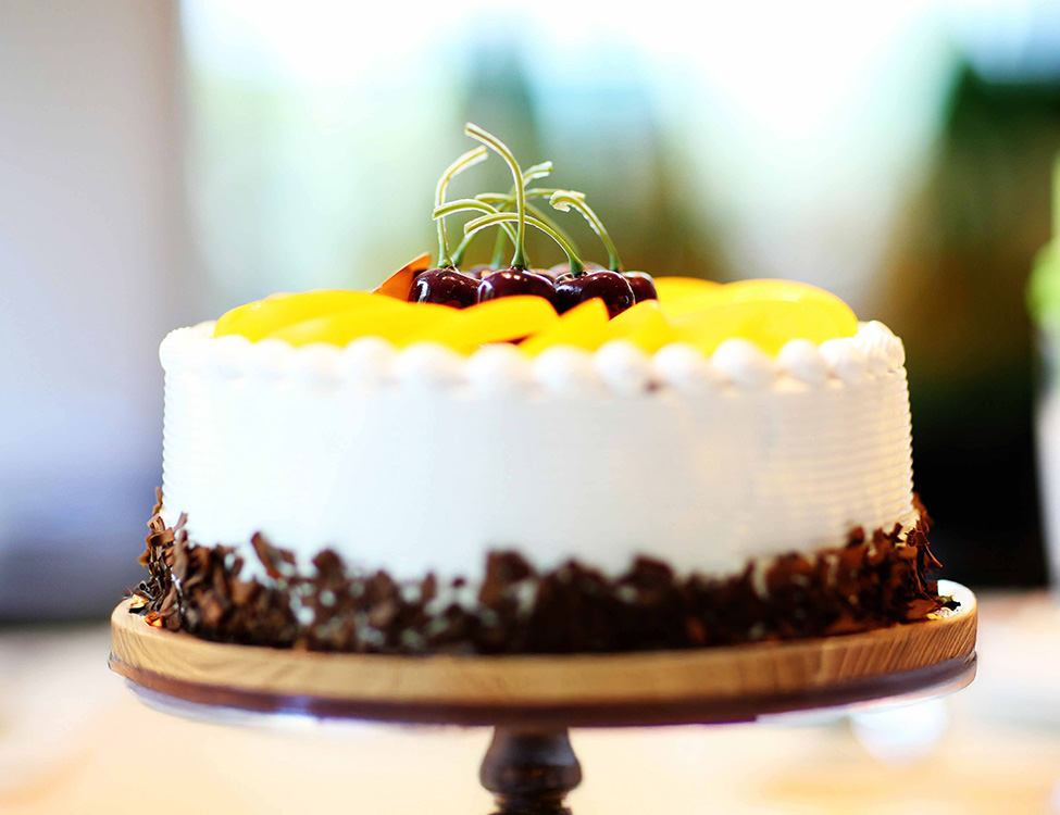 white cake with fruit on top and chocolate around the bottom on a cake plate